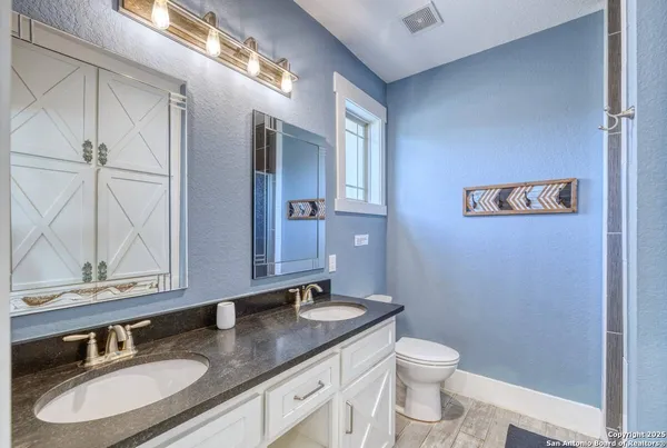 a bathroom with a granite countertop sink a toilet and a mirror