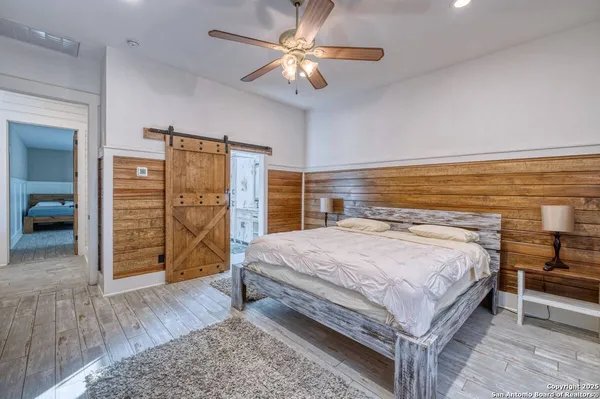 a spacious bedroom with a bed a dresser and a chandelier