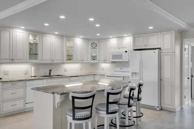 a large white kitchen with lots of counter space and furniture