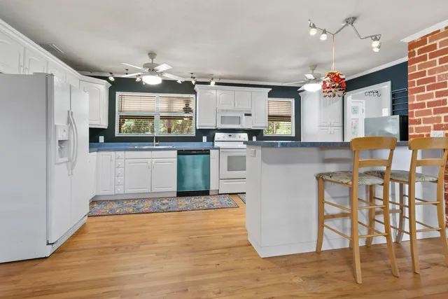 a kitchen with stainless steel appliances granite countertop a refrigerator a stove top oven and a dining table with wooden floor