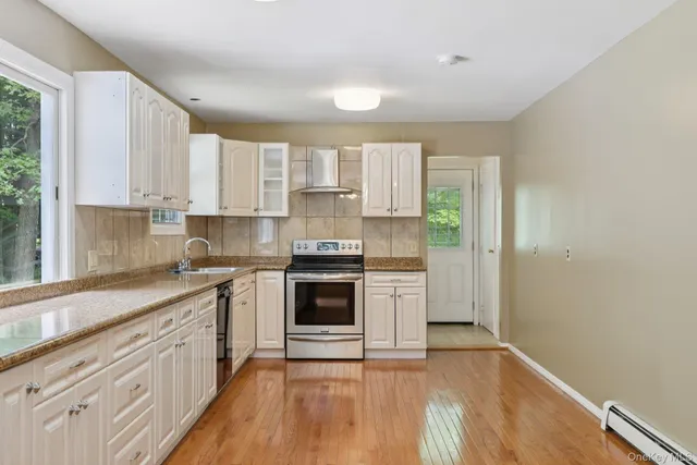 a kitchen with stainless steel appliances granite countertop a stove a sink and white cabinets