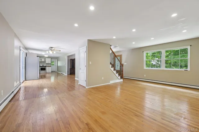 a view of a livingroom with wooden floor and a kitchen