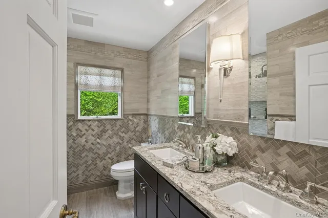 a bathroom with a granite countertop sink a toilet and a mirror