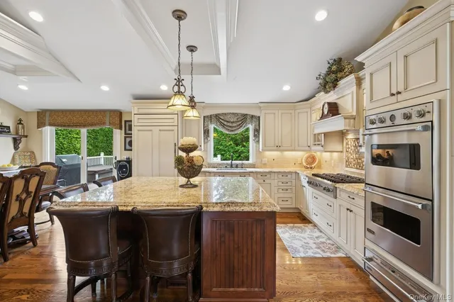 a kitchen with stainless steel appliances granite countertop a stove a sink dishwasher a dining table and chairs with wooden floor