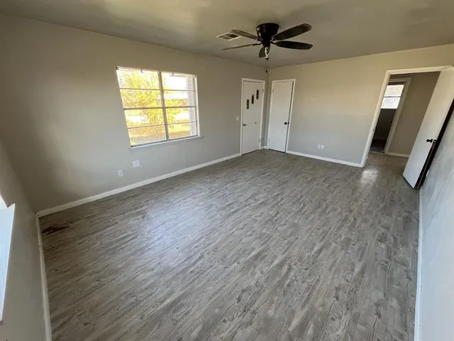 a view of empty room with wooden floor and fan