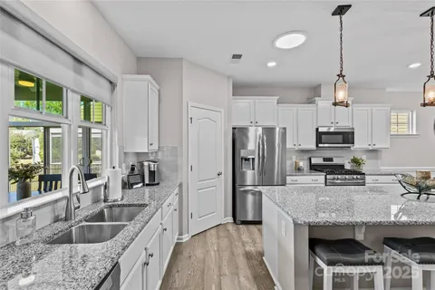 a kitchen with granite countertop kitchen island stainless steel appliances a sink and a center island