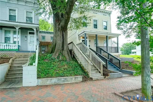 a view of a house with a small yard plants and large tree