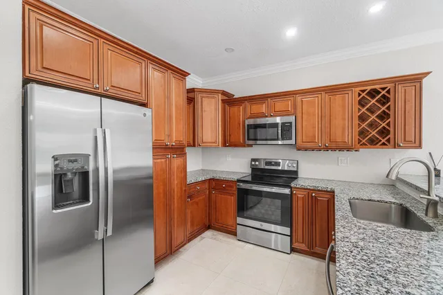 a kitchen with stainless steel appliances granite countertop a refrigerator a sink a stove top oven and a refrigerator