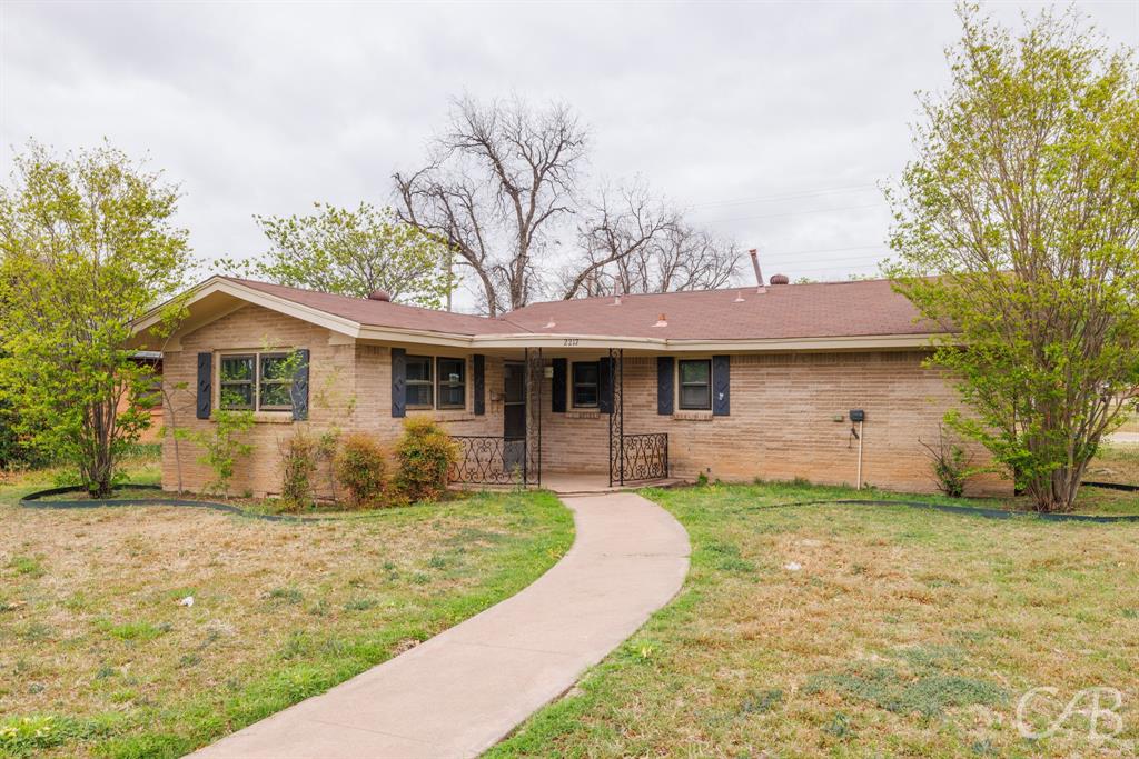 Ranch-style house featuring a porch, a front lawn, and brick siding