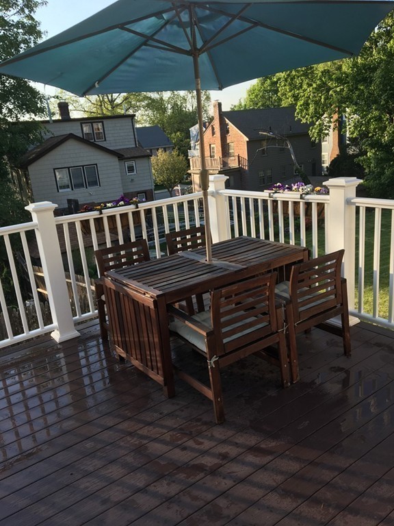 4 Latin Road Boston, MA 02132 - Photo 16 of 16 a view of a roof deck with table and chairs under an umbrella with wooden floor
