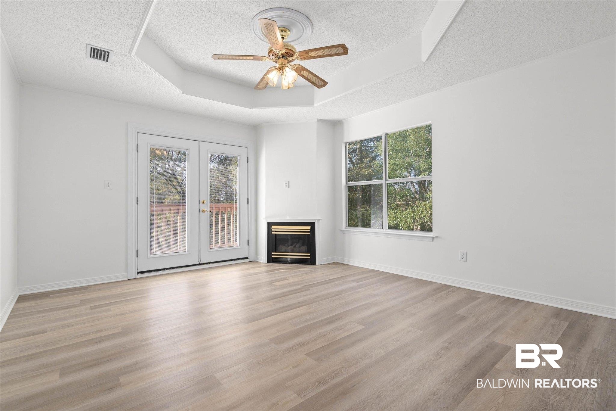 3847 Riviere Du Chien Road Mobile, AL 36693 - Photo 17 of 51 Unfurnished living room with french doors, a textured ceiling, light wood-style flooring, ceiling fan, and a raised ceiling