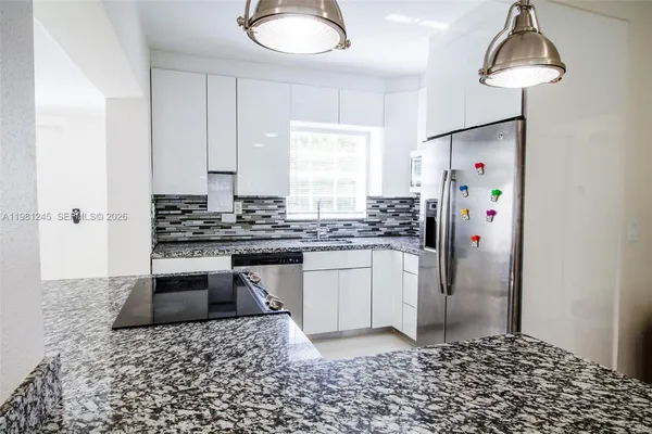 a kitchen with stainless steel appliances granite countertop a refrigerator a stove a sink and a counter space