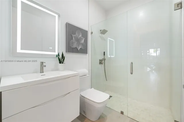 a bathroom with a toilet sink vanity shower and mirror