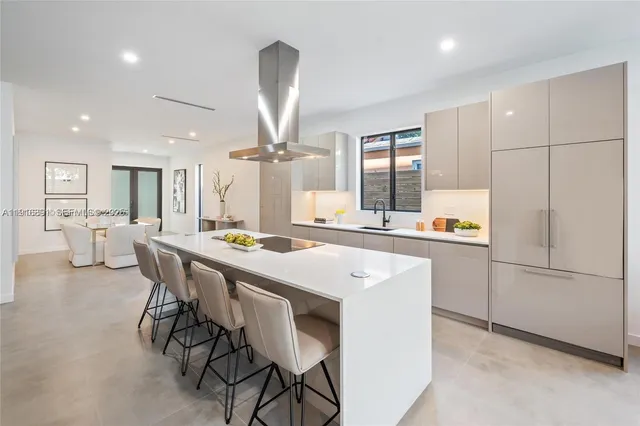 a kitchen with stainless steel appliances kitchen island granite countertop a table chairs sink and cabinets