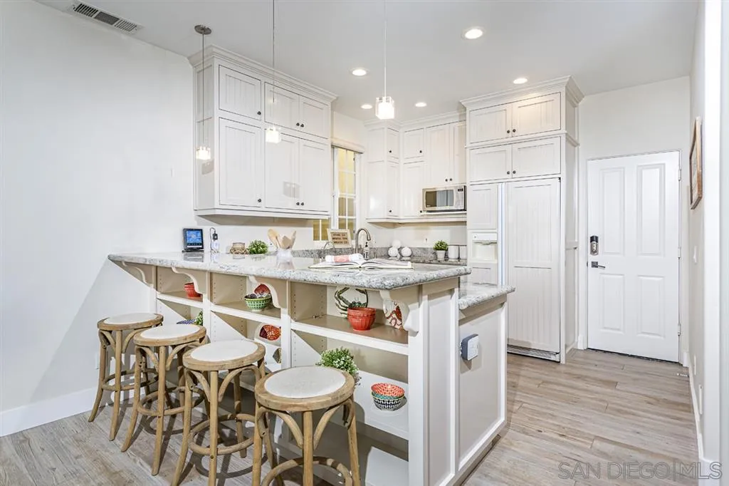930 10th Street Coronado, CA 92118 - Photo 3 of 25 a kitchen with stainless steel appliances kitchen island granite countertop a refrigerator a sink a stove and white cabinets with wooden floor