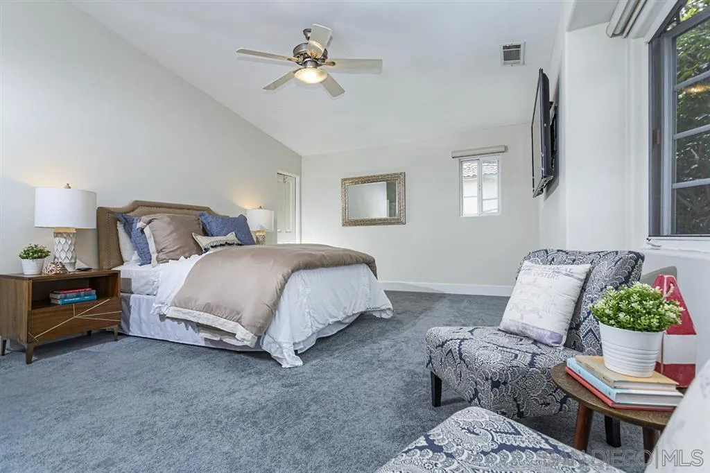 930 10th Street Coronado, CA 92118 - Photo 9 of 25 a spacious bedroom that has a bed a lamp on the small dresser a chandelier and a couch