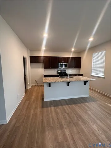 a living room with stainless steel appliances kitchen island hardwood floor and a sink