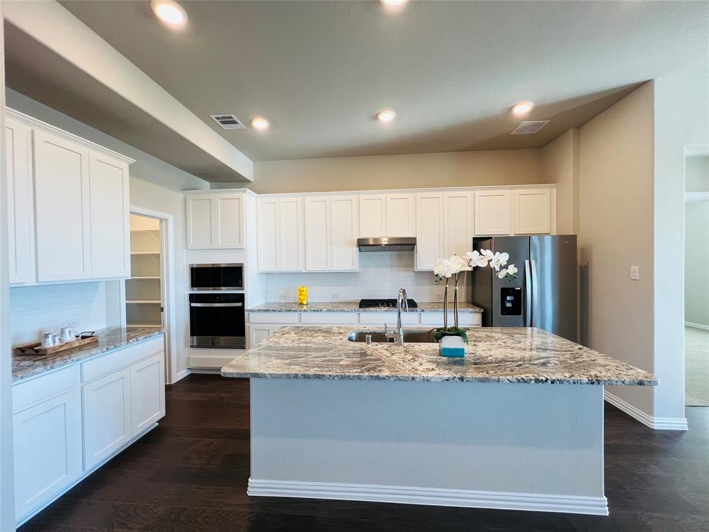 3305 Cross Shr Drive Anna, TX 75409 - Photo 11 of 31 Kitchen featuring sink, dark wood-type flooring, stainless steel appliances, a kitchen island with sink, and white cabinets