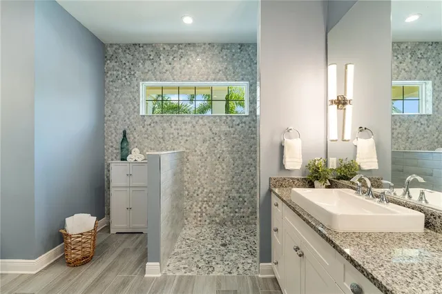 a kitchen with stainless steel appliances granite countertop a kitchen island a stove a sink a refrigerator and white cabinets with wooden floor