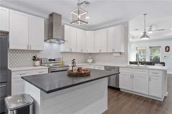 a kitchen with a sink dishwasher a stove a microwave oven and a dining table with wooden floor