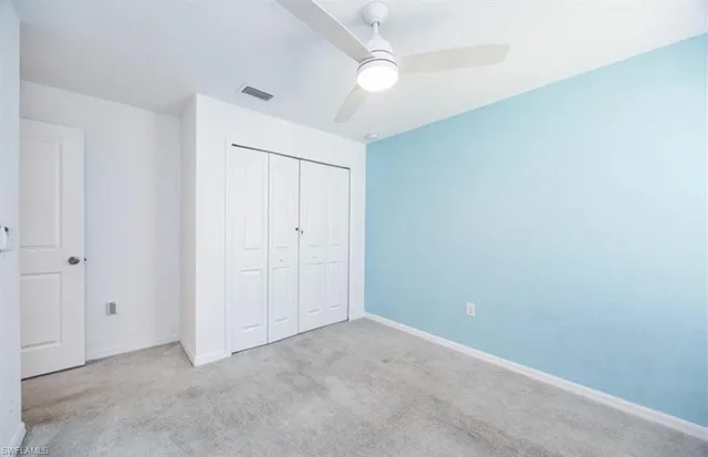 an empty room with closet and a ceiling fan