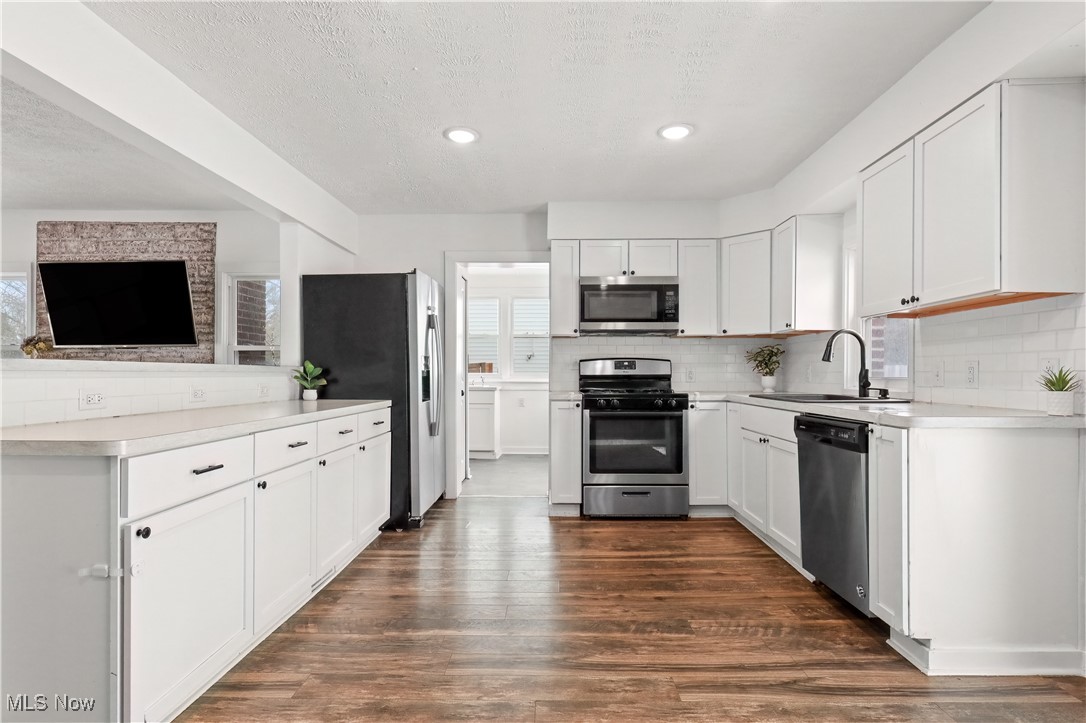 34549 Detroit Road Avon, OH 44011 - Photo 11 of 50 Kitchen with appliances with stainless steel finishes, breakfast bar, white cabinets, vinyl plank flooring, and a large 1st floor laundry