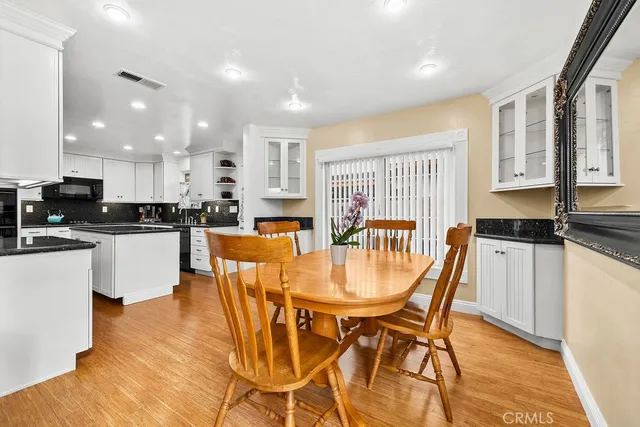 a kitchen with stainless steel appliances granite countertop a stove a sink a microwave a dining table and chairs with wooden floor