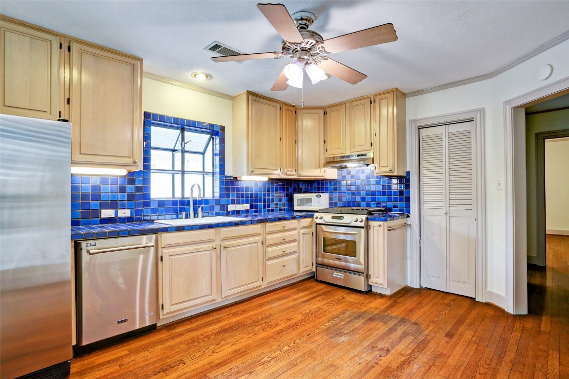 2324 Goldsmith Street, Unit B Houston, TX 77030 - Photo 4 of 19 a kitchen with stainless steel appliances a stove a sink dishwasher a refrigerator and white cabinets with wooden floor