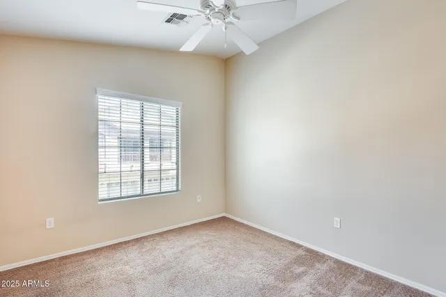 an empty room with a window and a ceiling fan