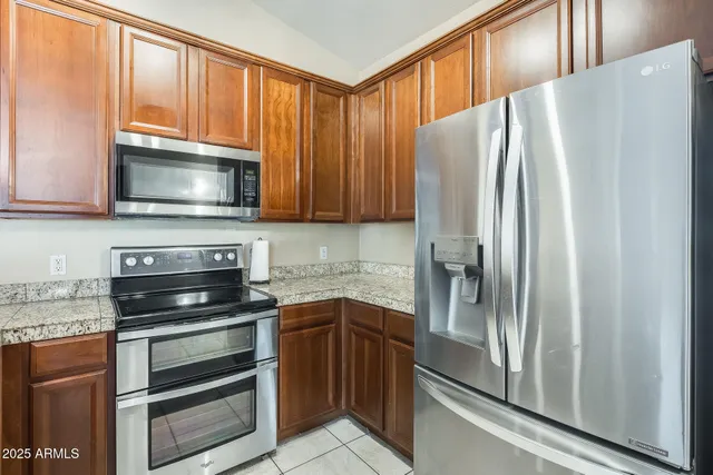 a kitchen with granite countertop a refrigerator stove and microwave