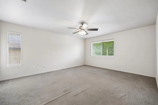 an empty room with windows and chandelier fan