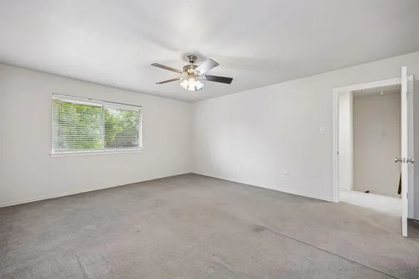 an empty room with windows and ceiling fan