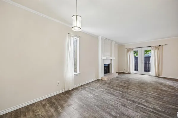a view of an empty room with window and wooden floor