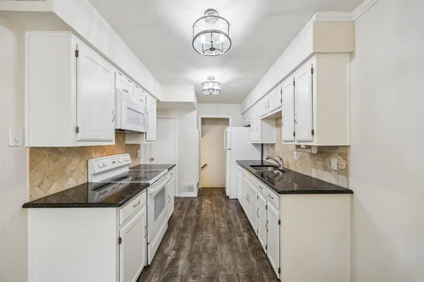 a kitchen with granite countertop a sink a stove oven and cabinets