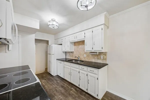 a kitchen with granite countertop white cabinets and white appliances