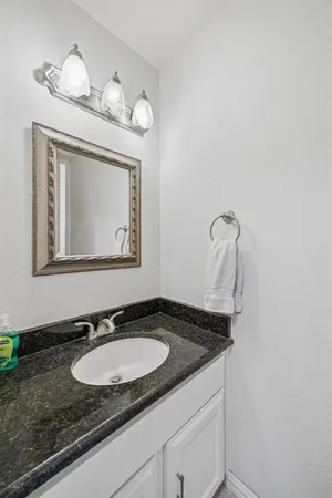 a bathroom with a granite countertop sink and a mirror