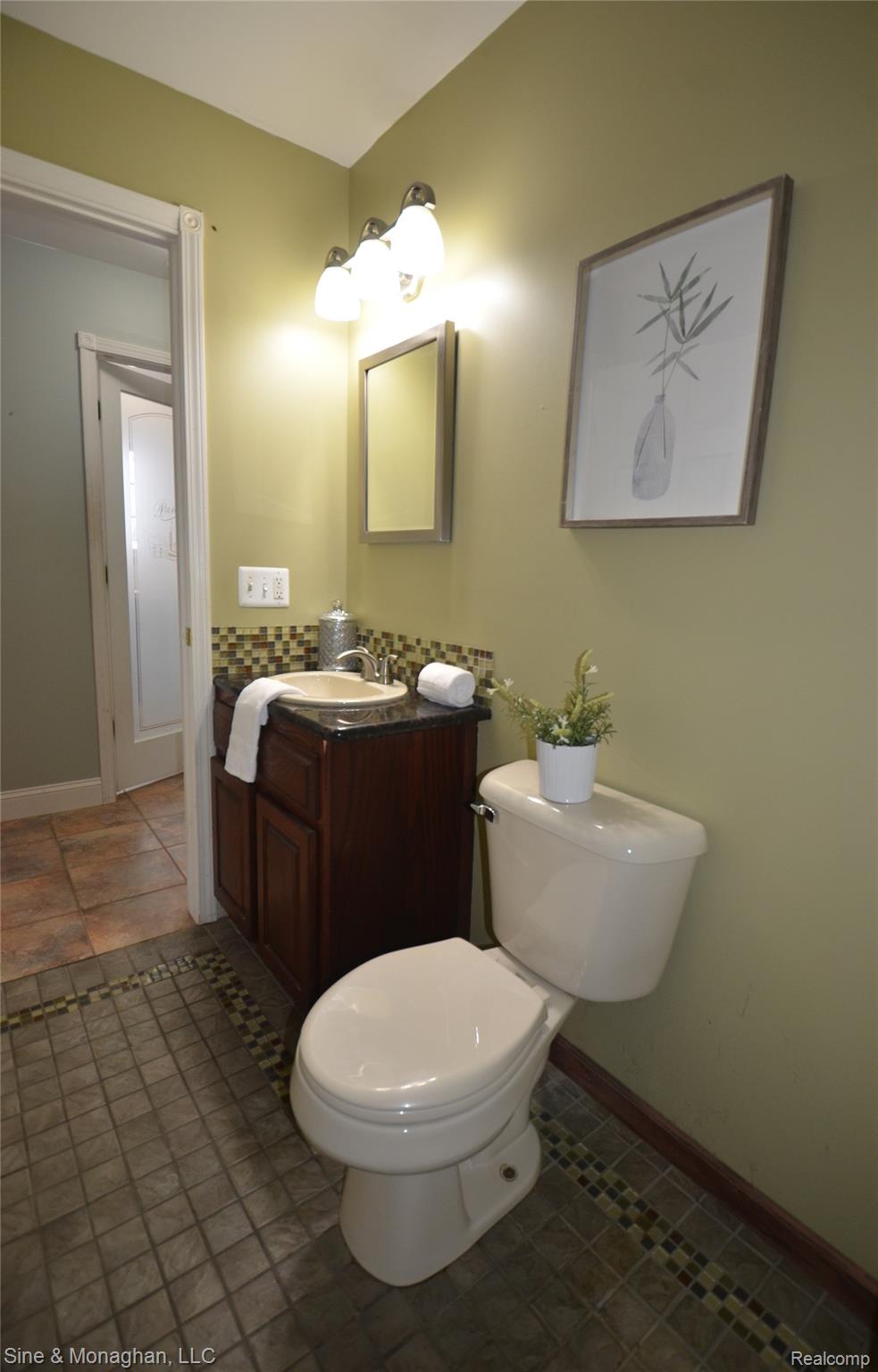 76152 Burman Road Richmond, MI 48062 - Photo 28 of 75 Half bathroom with vanity, dark tile patterned floors, and tasteful backsplash