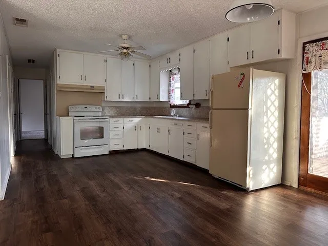 a kitchen with granite countertop white cabinets and white appliances
