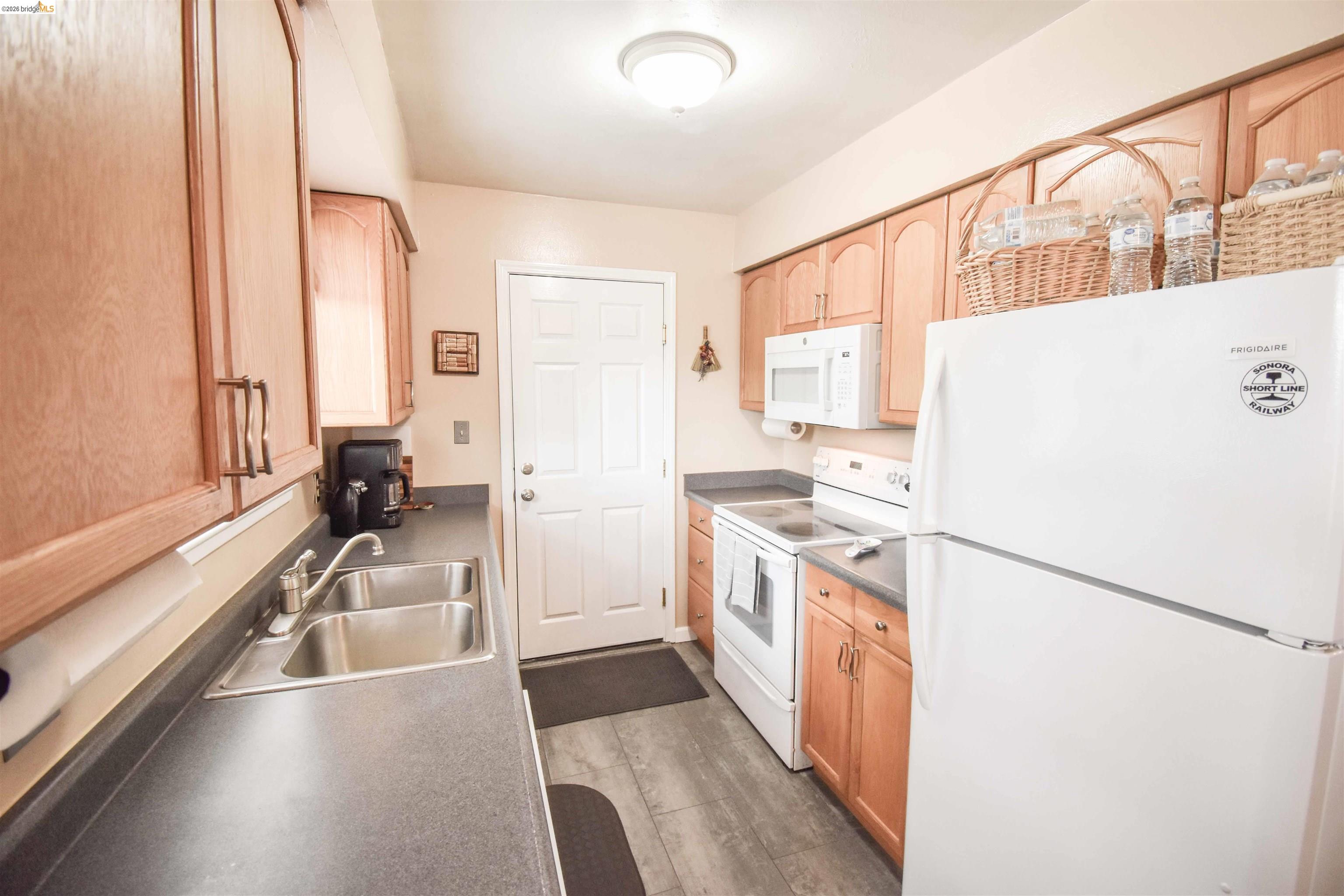 10569 Jim Brady Road Jamestown, CA 95327 - Photo 5 of 21 a kitchen with a refrigerator a stove and a sink with wooden floor