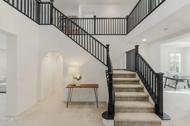 a kitchen with stainless steel appliances granite countertop a stove top oven a sink a refrigerator and chairs