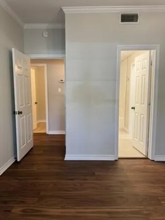 a view of an empty room with wooden floor and a door