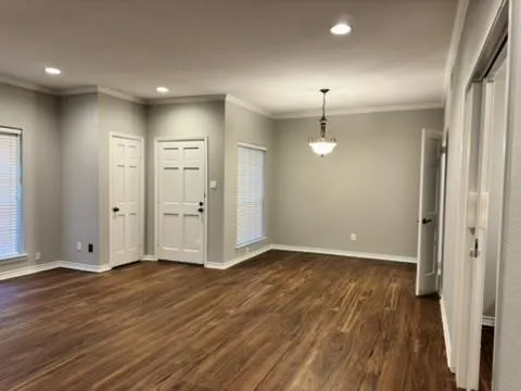 an empty room with wooden floor and bathroom view