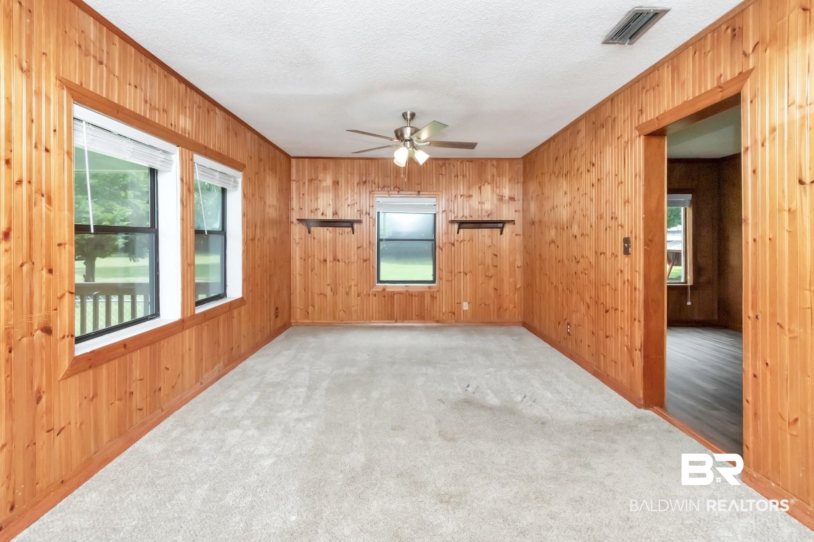 12751 Zanzibar Road Grand Bay, AL 36541 - Photo 5 of 30 Empty room featuring wood walls, carpet, ceiling fan, and a textured ceiling