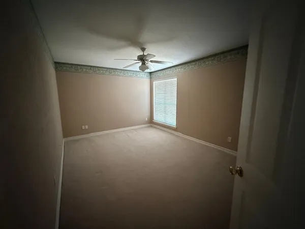 an empty room with a ceiling fan and a window