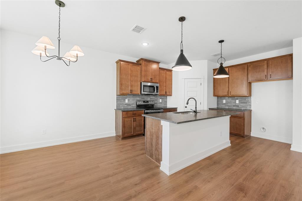 3000 Teasdale Road Lorena, TX 76655 - Photo 5 of 16 a kitchen with kitchen island granite countertop stainless steel appliances a sink a counter top space cabinets and wooden floor