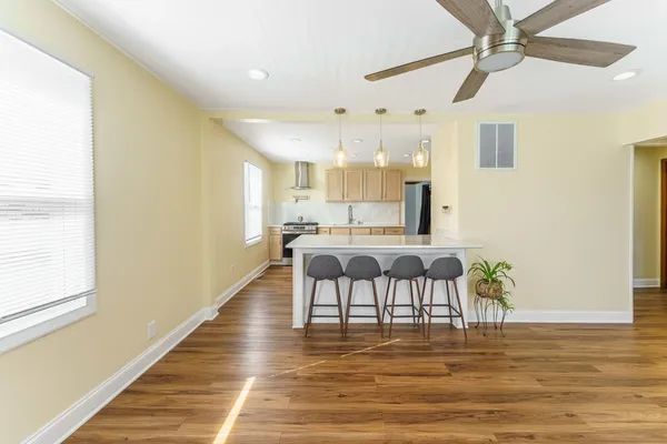 a view of an empty room with wooden floor fireplace and a window