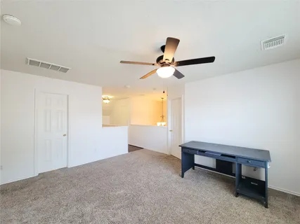 an empty room with windows and chandelier fan