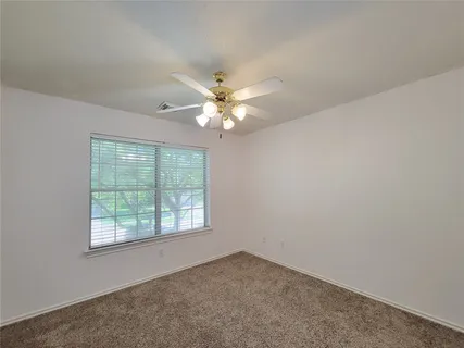 an empty room with a chandelier fan and closet