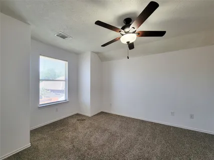 an empty room with windows and chandelier fan