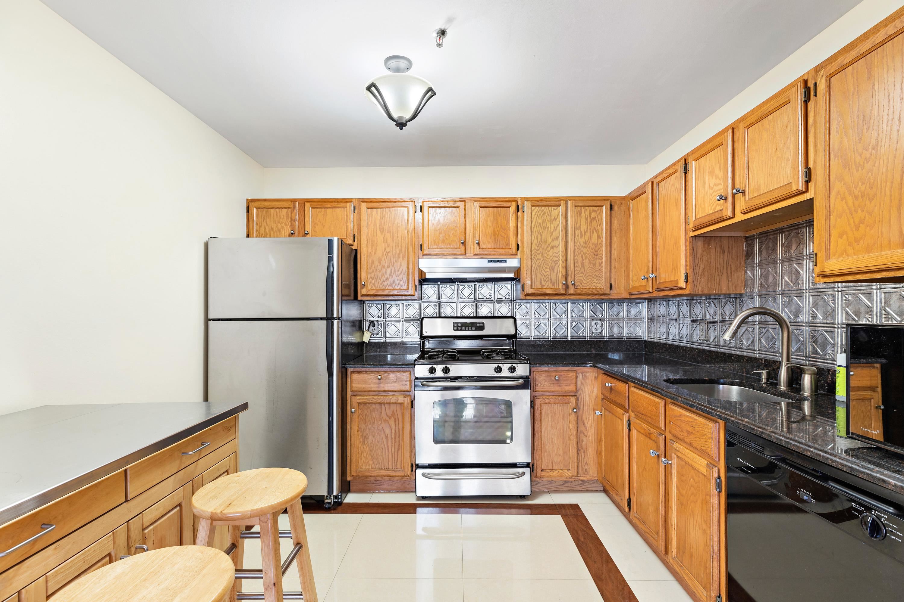 56 Ferguson Street, Unit C2 Newark, NJ 07105 - Photo 6 of 16 a kitchen with stainless steel appliances granite countertop a stove a sink dishwasher a refrigerator and a dining table with wooden cabinet